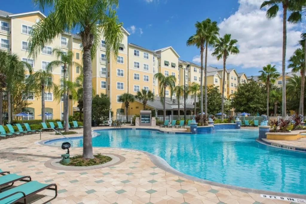 Palm-lined outdoor pool and yellow guest buildings at Residence Inn by Marriott Orlando at SeaWorld