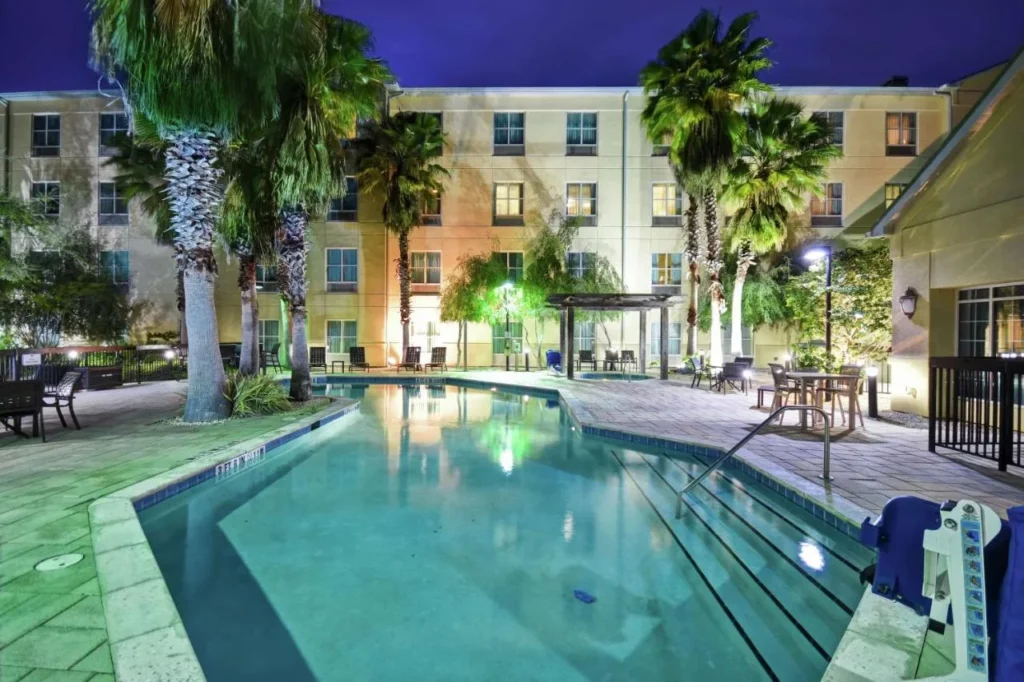 Piscina al aire libre con palmeras iluminada por la noche en Homewood Suites by Hilton Ocala at Heath Brook