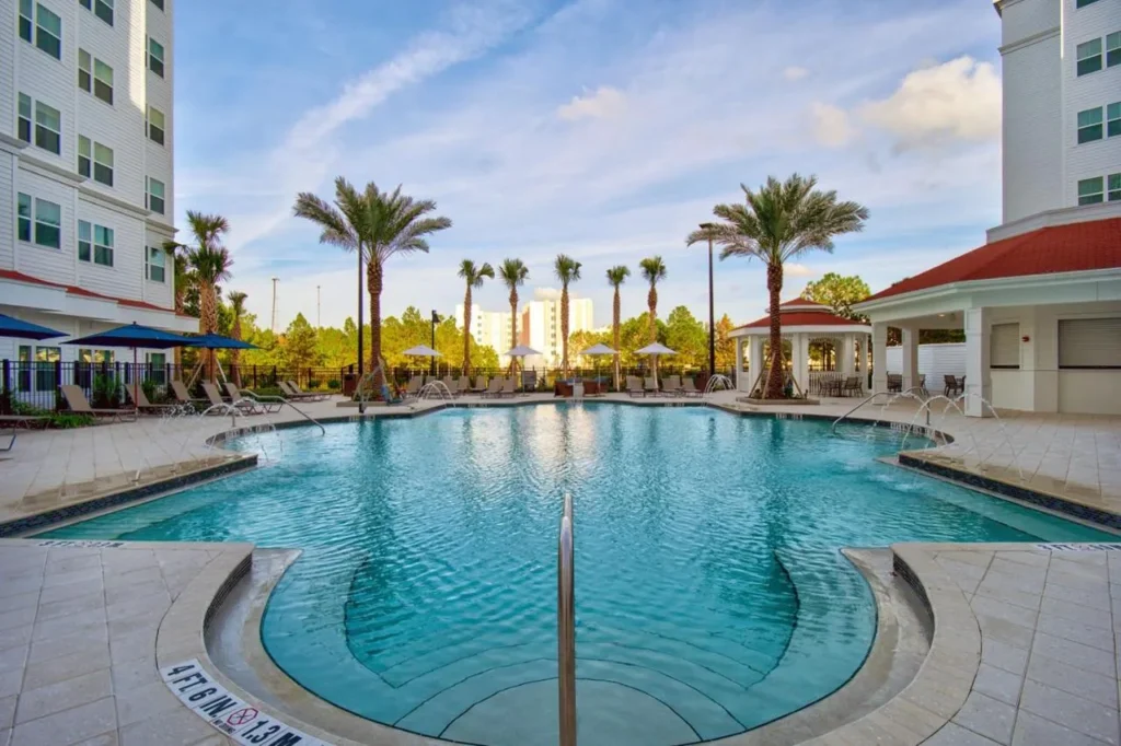 Palm-lined outdoor pool with fountain jets at Residence Inn Orlando Flamingo Crossings