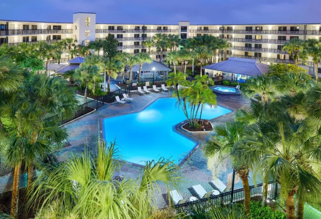 Palm-lined pool courtyard at dusk beside the suite buildings of Staybridge Suites Orlando Royale Parc Suites