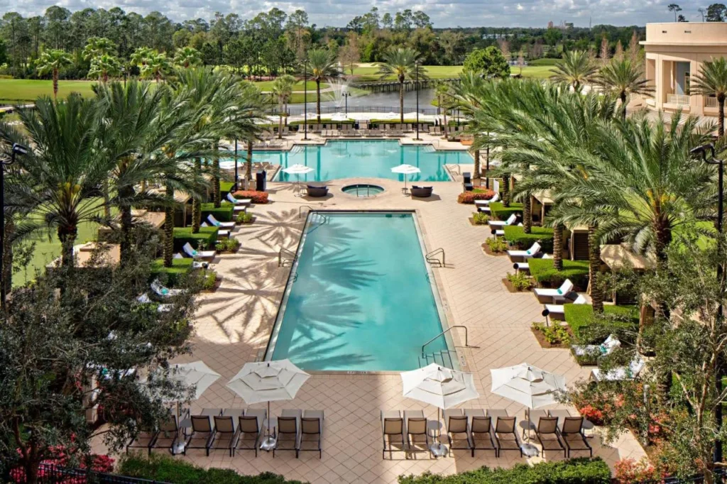 Terraza de la piscina bordeada de palmeras con vista a la piscina y al campo de golf en Waldorf Astoria Orlando