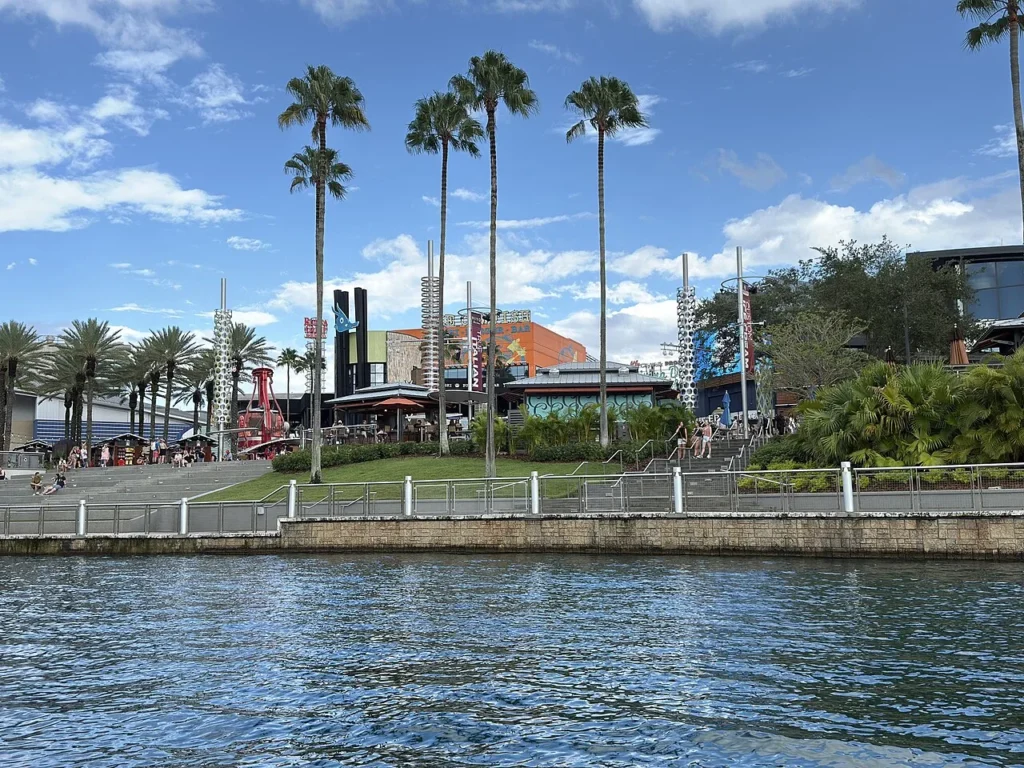 Terrazas y restaurantes Universal CityWalk bordeados de palmeras vistos a través de la vía fluvial en una tarde soleada