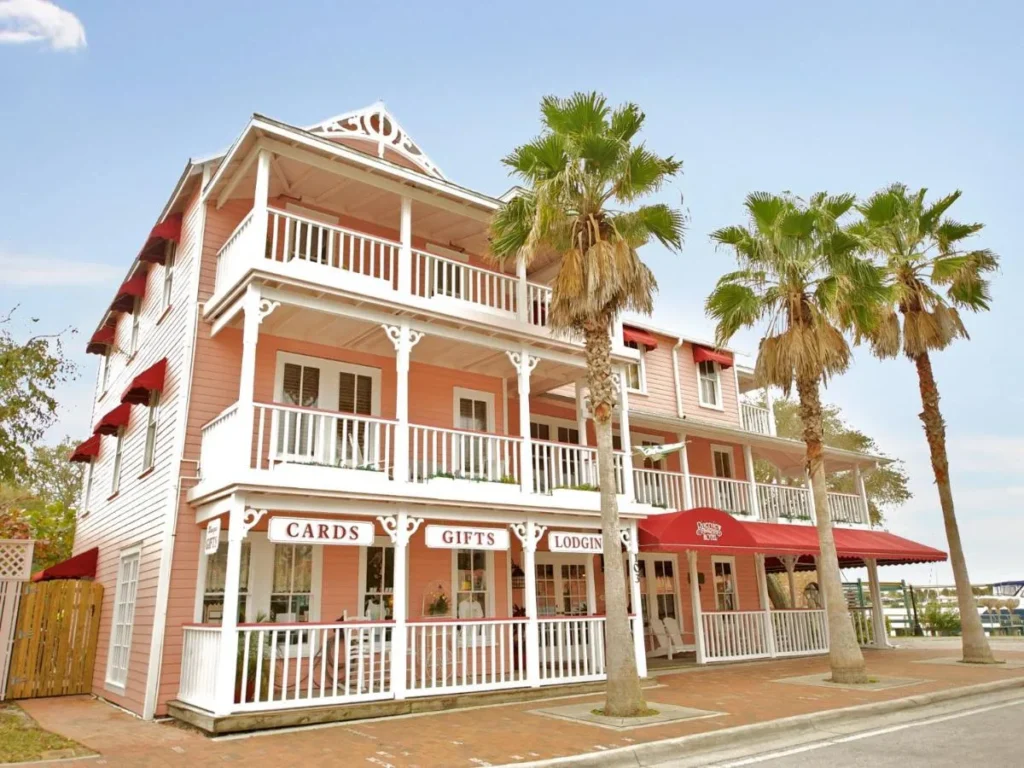 Pink Victorian facade with white balconies and palm trees at The Riverview Hotel on Flagler Avenue