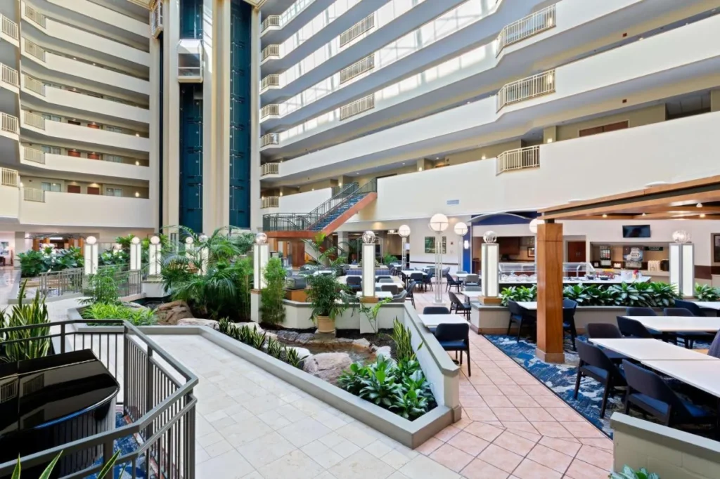 Atrio lleno de plantas de varios pisos con mesas de comedor en Embassy Suites by Hilton Tampa USF