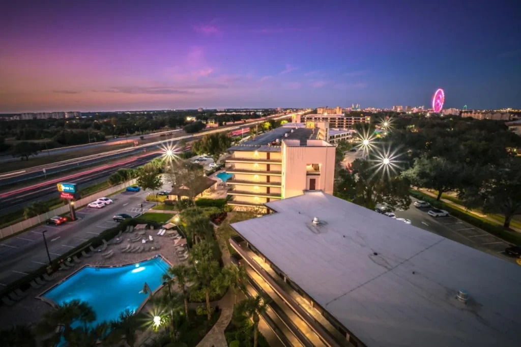 Piscina y tumbonas al atardecer en Rosen Inn at Pointe Orlando, con el Orlando Eye más allá