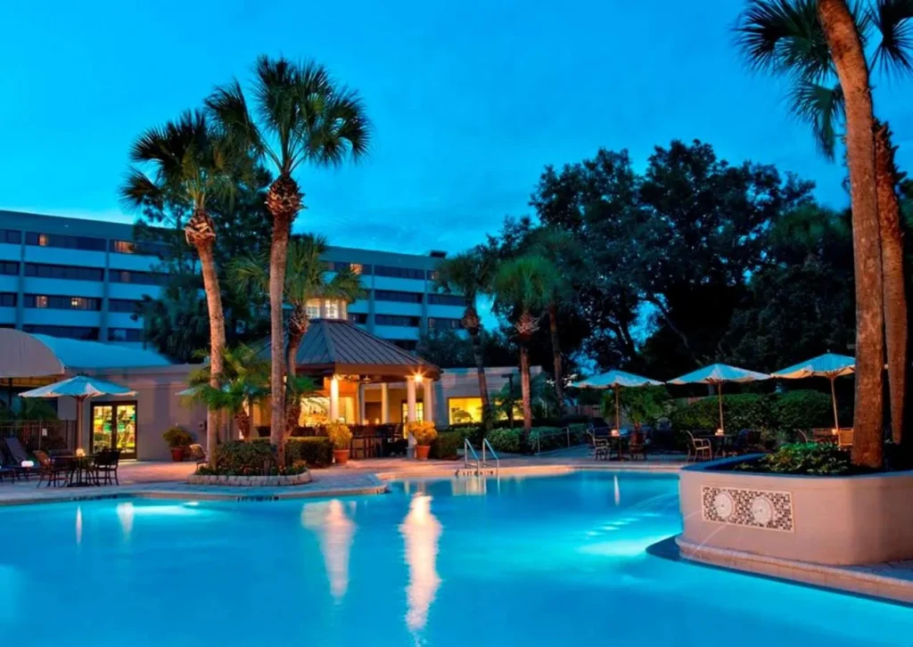 Pool at dusk with palm trees and a lit gazebo at DoubleTree Suites Disney Springs