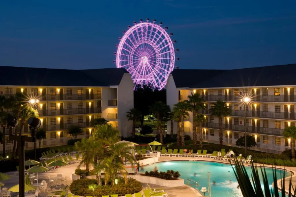 Courtyard de la piscina por la noche con el volante iluminado Orlando Eye detr&aacute;s de Avanti International Resort