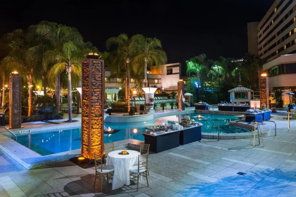 Cubierta de la piscina por la noche con columnas de fuego y mesas de buffet, Hilton Orlando Lake Buena Vista