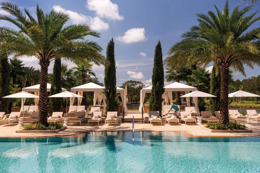 Pool deck lined with white cabanas, loungers and palm trees at Four Seasons Resort Orlando