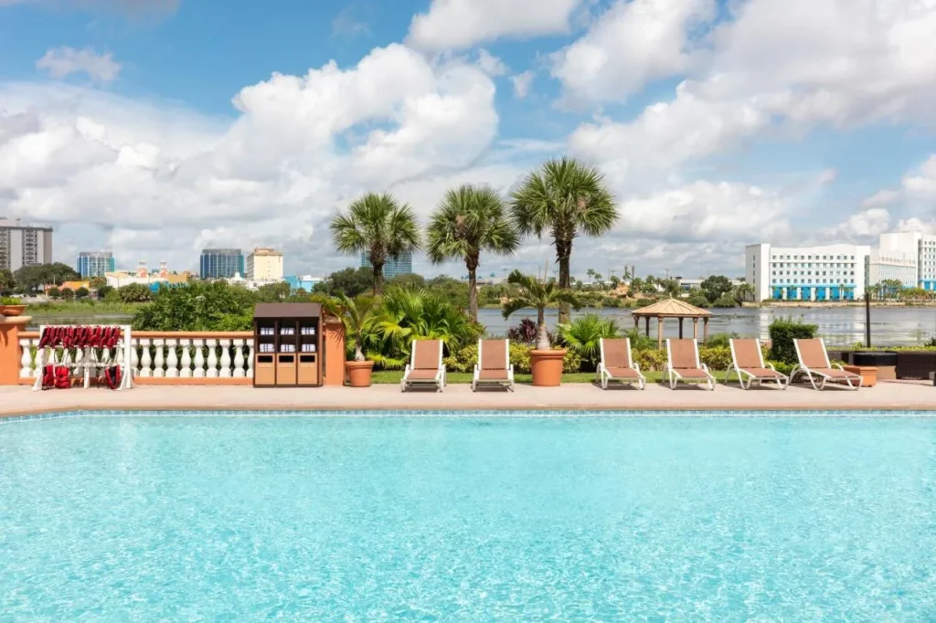 Pool deck with lounge chairs, palms and a gazebo beside the lake at Westgate Palace