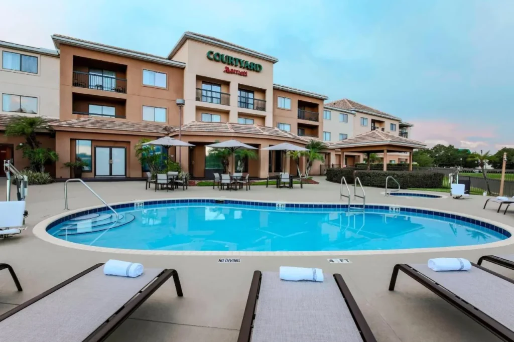 Terraza de la piscina con tumbonas y sombrillas frente al Courtyard by Marriott Orlando Lake Mary/North