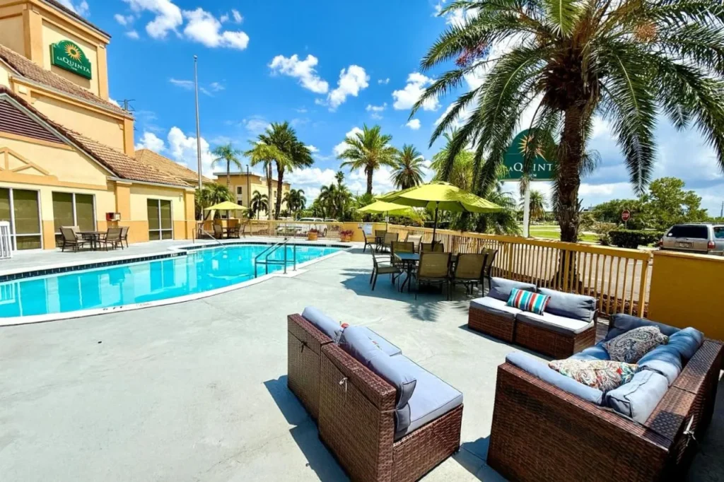 Pool deck with wicker sofas, green umbrellas and hotel tower at La Quinta Orlando Universal area