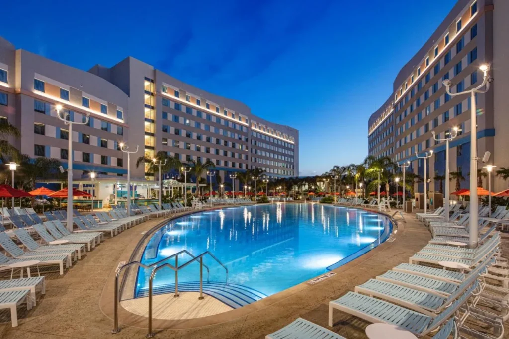 Piscina iluminada al atardecer entre las alas curvas del hotel Endless Summer Surfside Inn and Suites