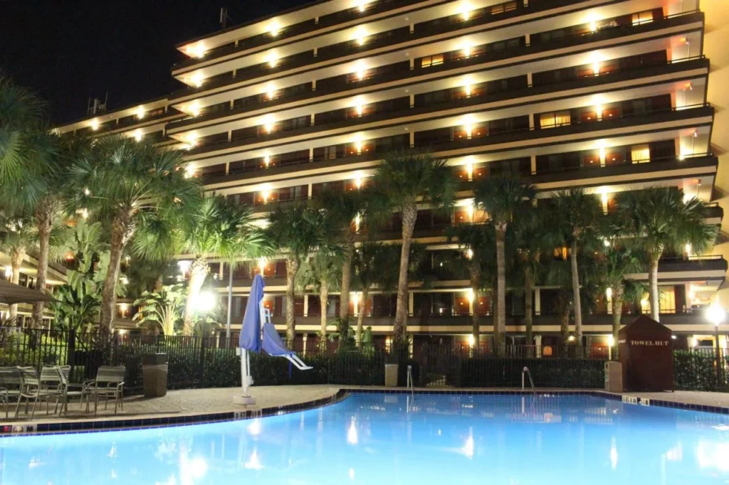 Pool lit at night below the multi-story guest building at Rosen Inn at Pointe Orlando
