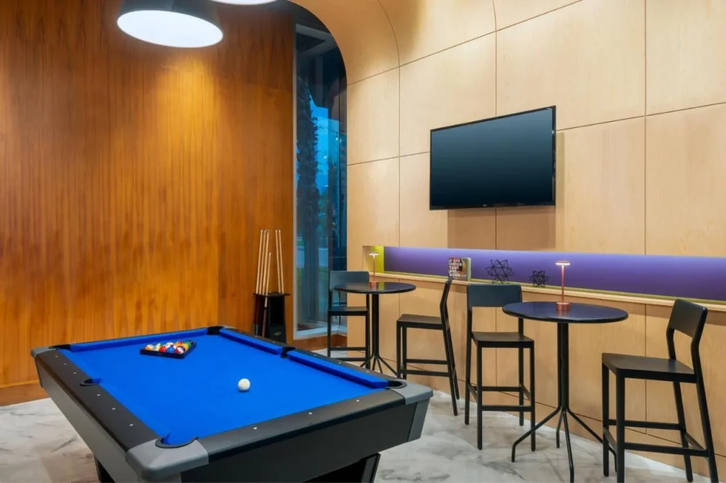 Mesa de billar y asientos altos en un salón con paneles de madera en el Aloft Orlando Downtown
