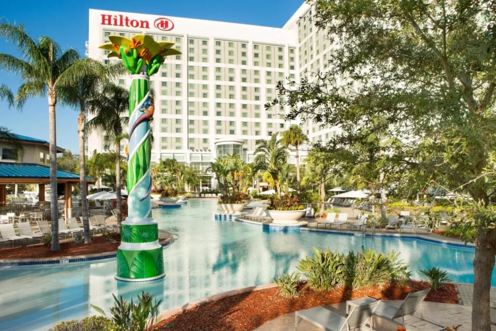 Pool with a frog-topped column below the Hilton Orlando tower and its rooftop sign