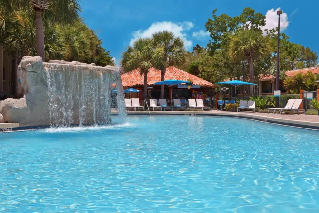 Piscina con cascada de rocas y palmeras en el DoubleTree by Hilton Orlando Theme Park Resort
