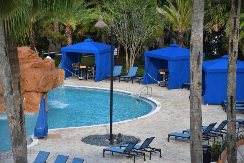 Pool with a rock waterfall, blue cabanas and lounge chairs at Wyndham Lake Buena Vista