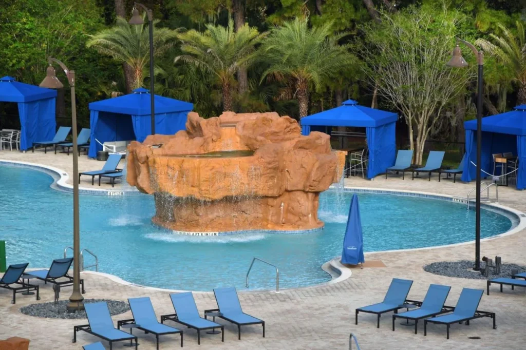 Piscina con cascada de roca, caba&ntilde;as azules y tumbonas en Wyndham Lake Buena Vista