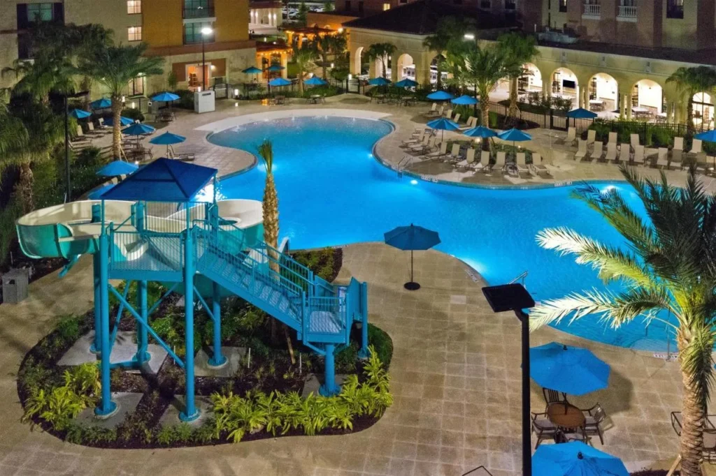 Piscina con una torre de tobog&aacute;n iluminada por la noche en Homewood Suites Flamingo Crossings