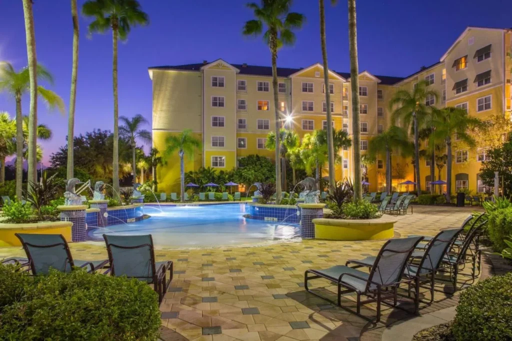 Piscina con fuentes de delfines y edificios de invitados amarillos al atardecer, Residence Inn Orlando at SeaWorld