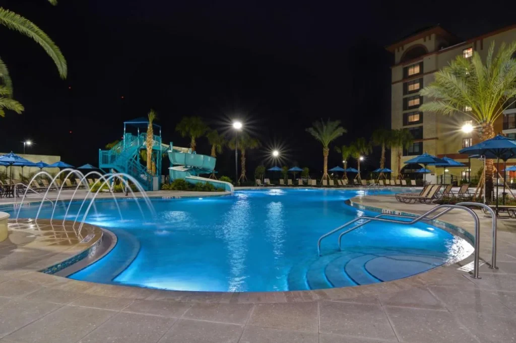 Piscina con fuentes y un tobogán en espiral por la noche en Home2 Suites Orlando Flamingo Crossings
