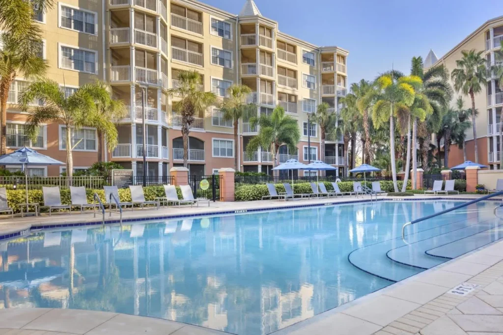 Piscina con tumbonas y palmeras junto a los edificios de la villa en Hilton Grand Vacations Club SeaWorld Orlando