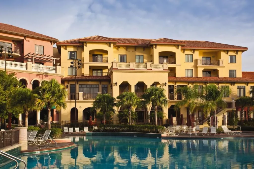 Piscina con tumbonas frente a un edificio amarillo de estilo mediterráneo en Club Wyndham Bonnet Creek