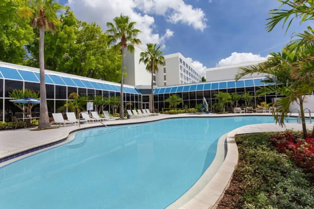 Piscina con palmeras junto a un ala con paredes de vidrio en el Holiday Inn Resort Kissimmee by the Parks