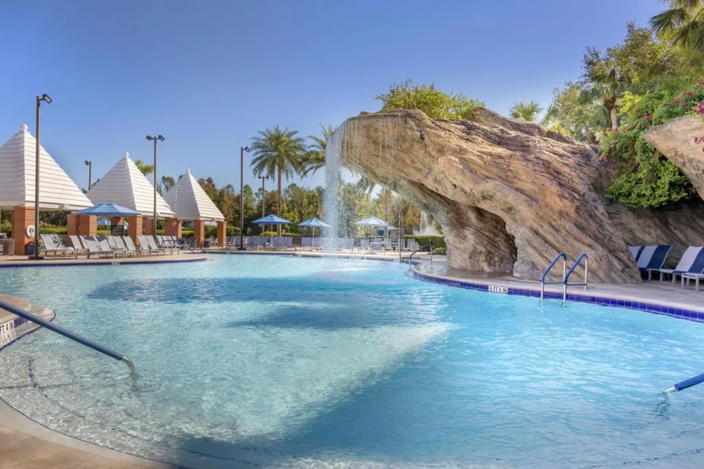 Piscina con cascada de roca y cabañas con techo piramidal en Hilton Grand Vacations Club SeaWorld Orlando