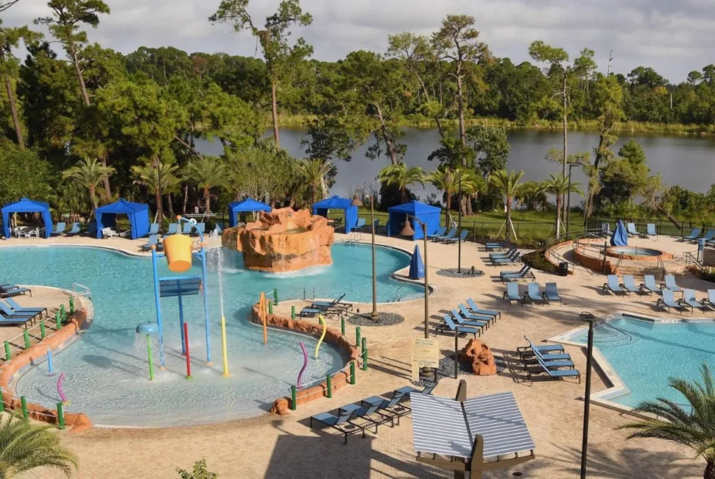 Pool with splash play features, blue cabanas and a lake view at Wyndham Lake Buena Vista