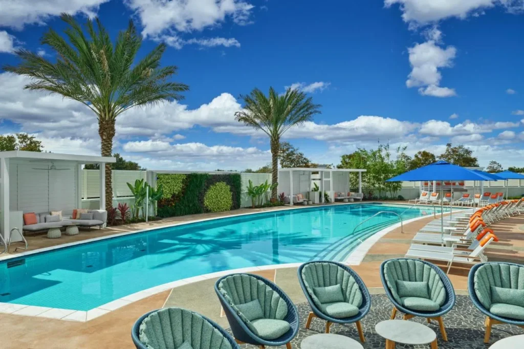 Pool with teal shell chairs, white cabanas and blue umbrellas at Walt Disney World Swan Reserve