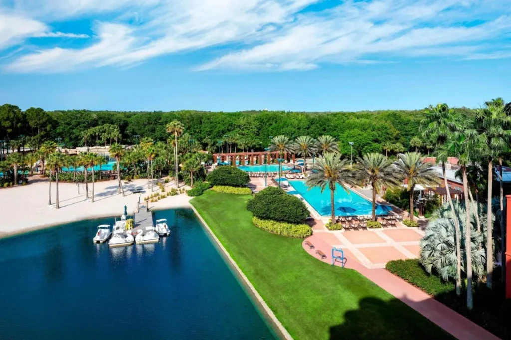 Piscinas, playa de arena blanca y botes de remo de cisne junto al lago en Walt Disney World Dolphin
