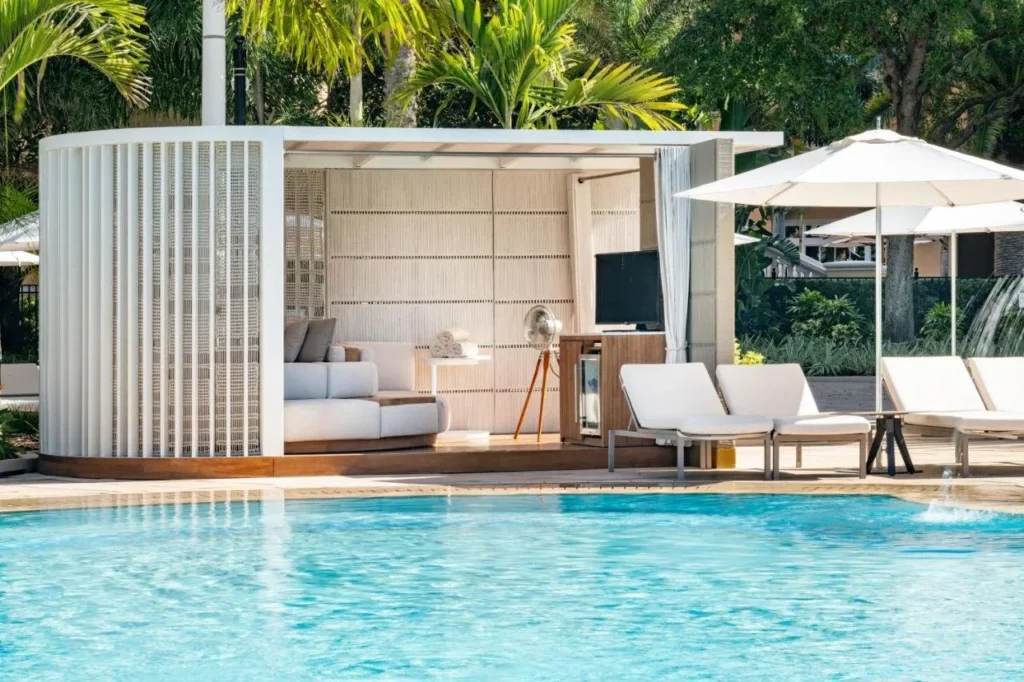 Cabaña junto a la piscina con asientos acolchados, TV y tumbonas blancas en The Ritz-Carlton Orlando, Grande Lakes