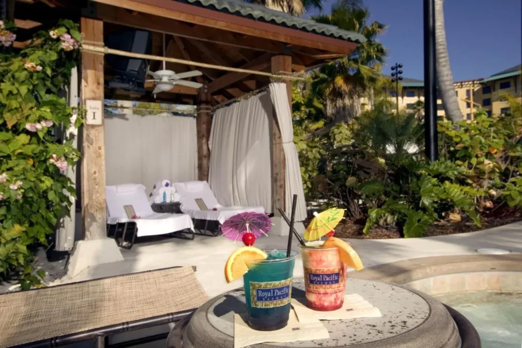 Caba&ntilde;a junto a la piscina con tumbonas, ventilador de techo y bebidas tropicales en Loews Royal Pacific Resort