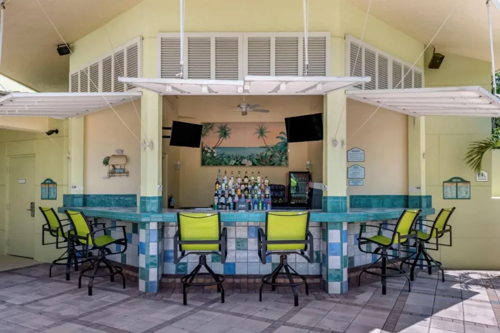 Bar Daiquiri junto a la piscina con mostrador de azulejos y taburetes de color verde lima en Comfort Suites Maingate East