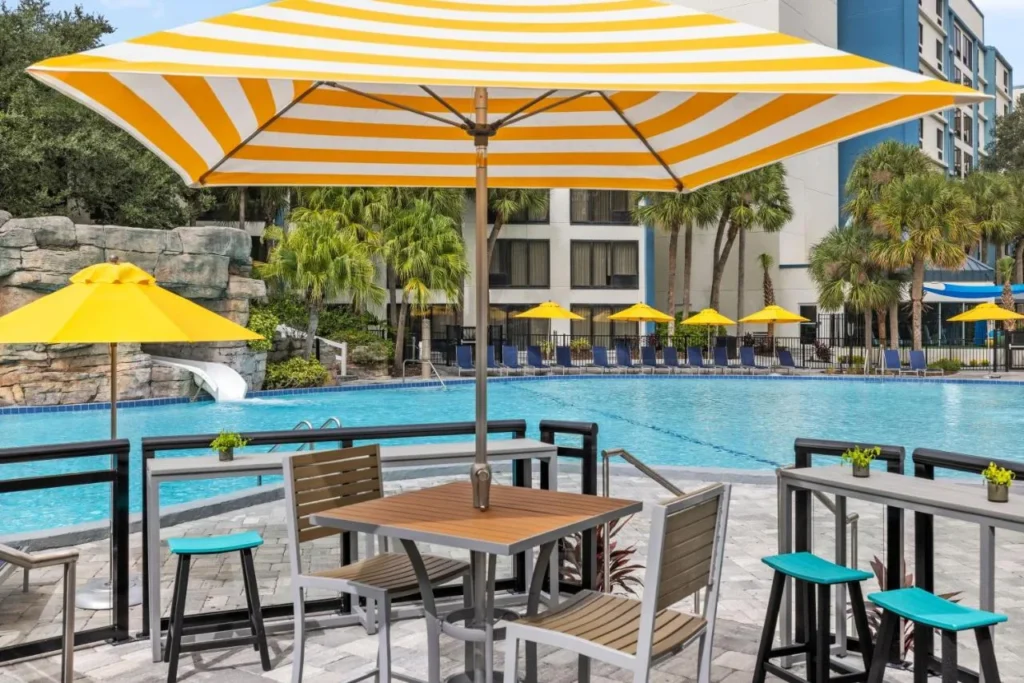 Mesa de billar bajo un paraguas a rayas cerca del tobog&aacute;n de agua en Delta Hotels Orlando Celebration