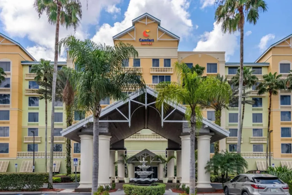 Porte-cochere entrance with fountain and palms at Comfort Suites Maingate East in Kissimmee