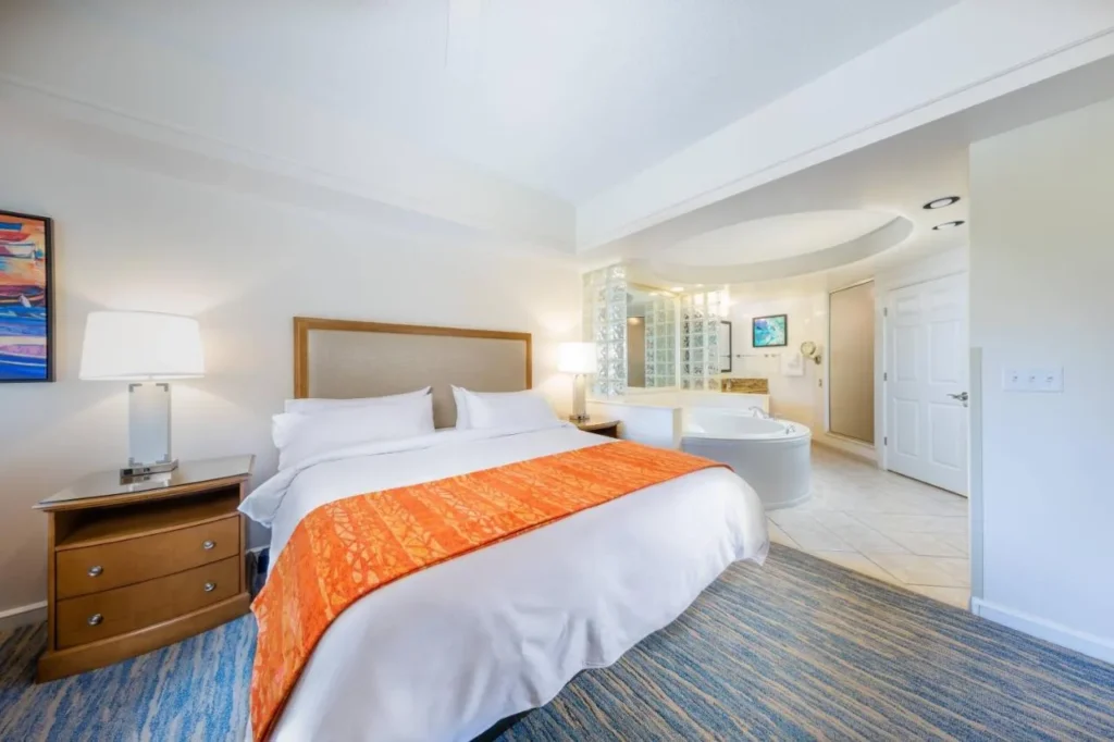 Dormitorio principal con una cama grande y una ba&ntilde;era de hidromasaje abierta en el Marriott's Cypress Harbour