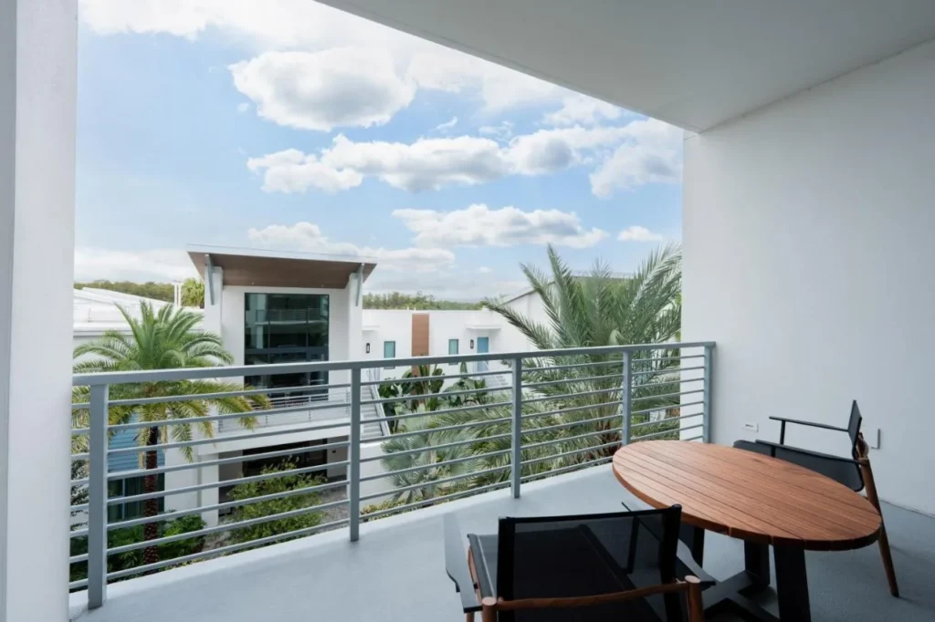 Private balcony with wooden table and chairs overlooking palms at Evermore Orlando Resort