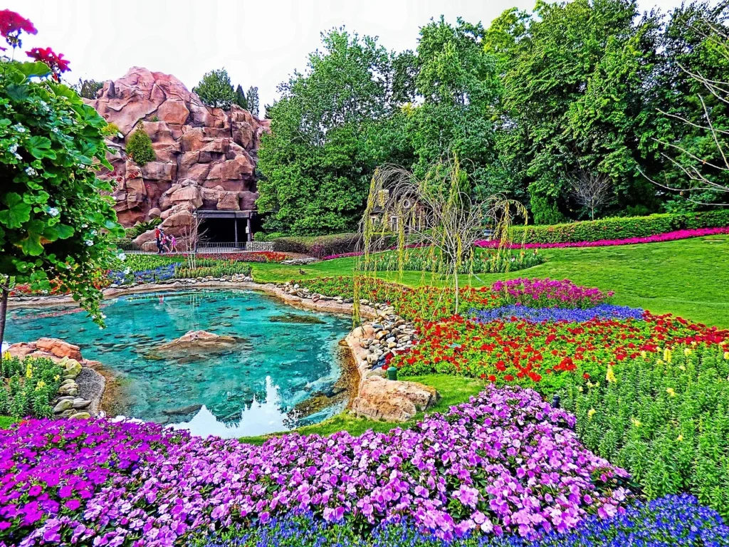 Purple flower beds and a turquoise pond at EPCOT's Canada pavilion, Flower and Garden Festival