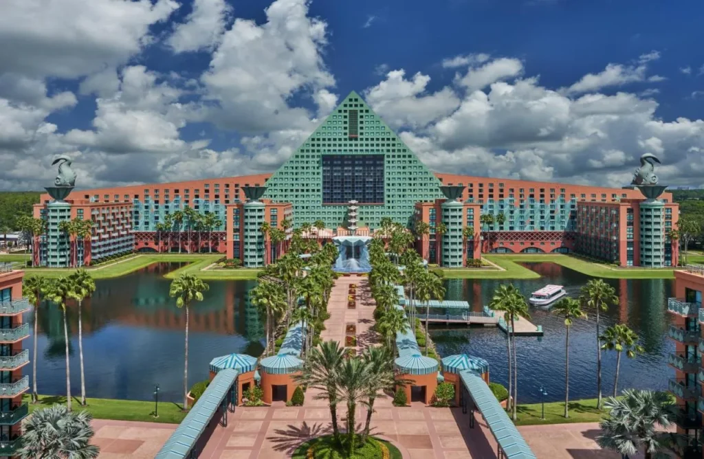 Walt Disney World Dolphin en forma de pir&aacute;mide m&aacute;s all&aacute; de una calzada bordeada de palmeras, laguna y muelle de taxis acu&aacute;ticos