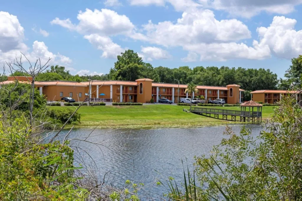 Quality Inn & Suites Mt Dora North buildings seen across a pond with a gazebo dock