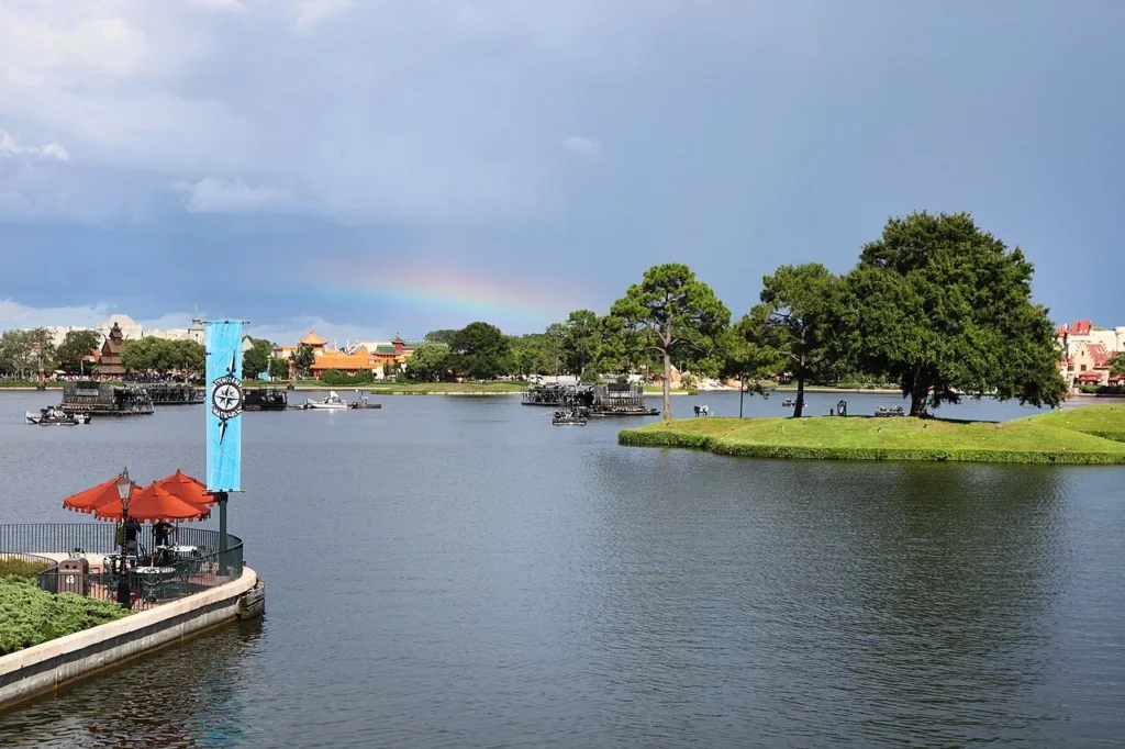 Rainbow over World Showcase Lagoon at EPCOT with pavilions and a small wooded island