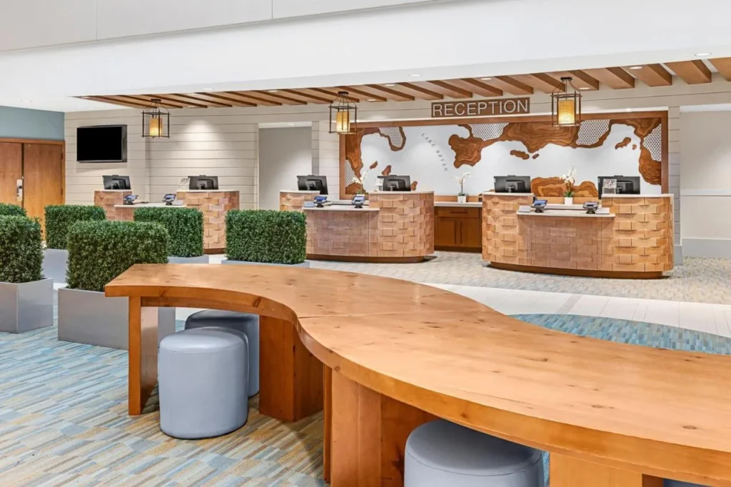 Escritorios de recepción con un mapa de lago de madera tallada y una mesa común curva en Sheraton Vistana Resort