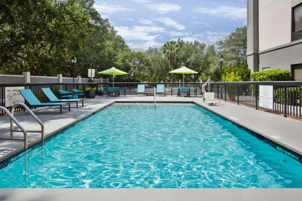 Piscina exterior rectangular con tumbonas y sombrillas en Hampton Inn & Suites Lady Lake/The Villages