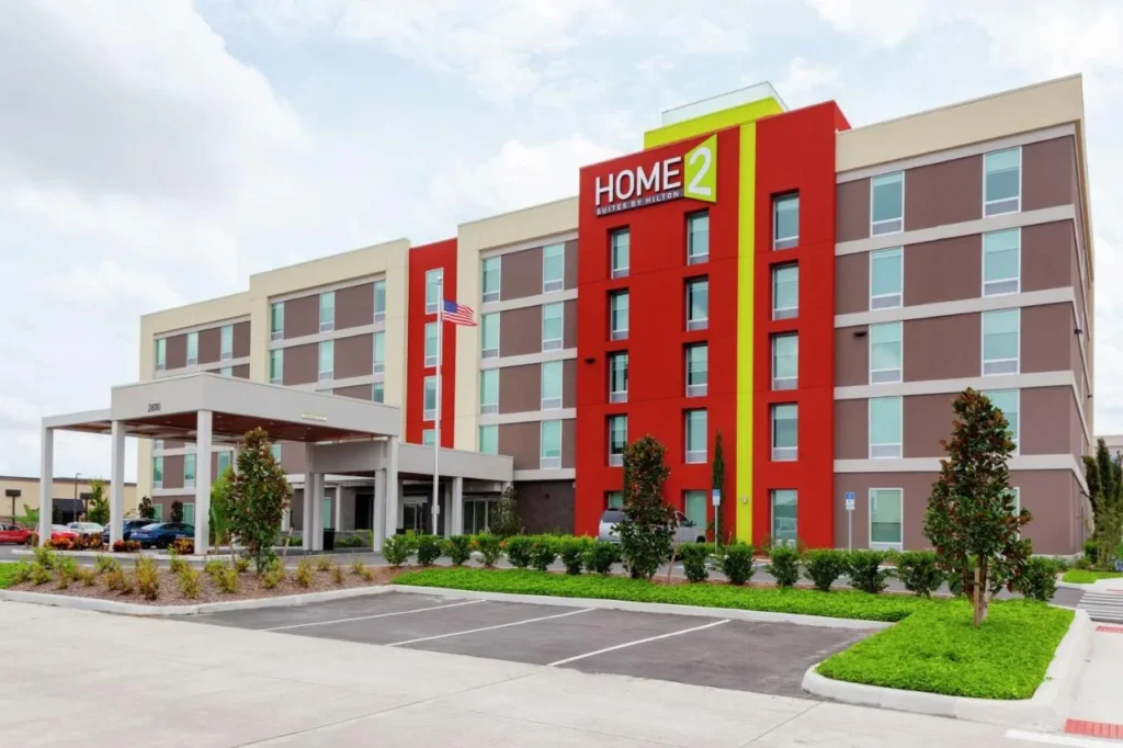 Fachada roja y beige con entrada cubierta en Home2 Suites by Hilton Orlando South Park