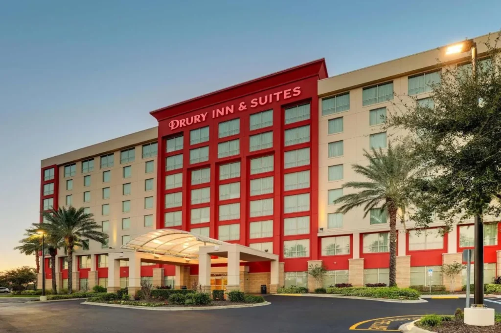 Exterior rojo y blanco de varios pisos y dosel de entrada en Drury Inn & Suites Orlando near Universal