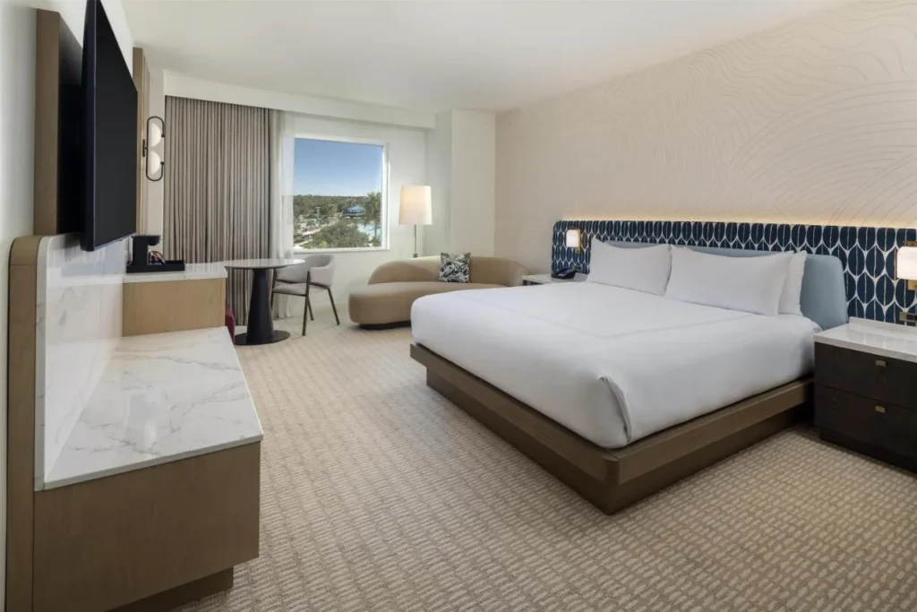 Refreshed king guest room with sofa, small table and pool-view window at Hilton Orlando