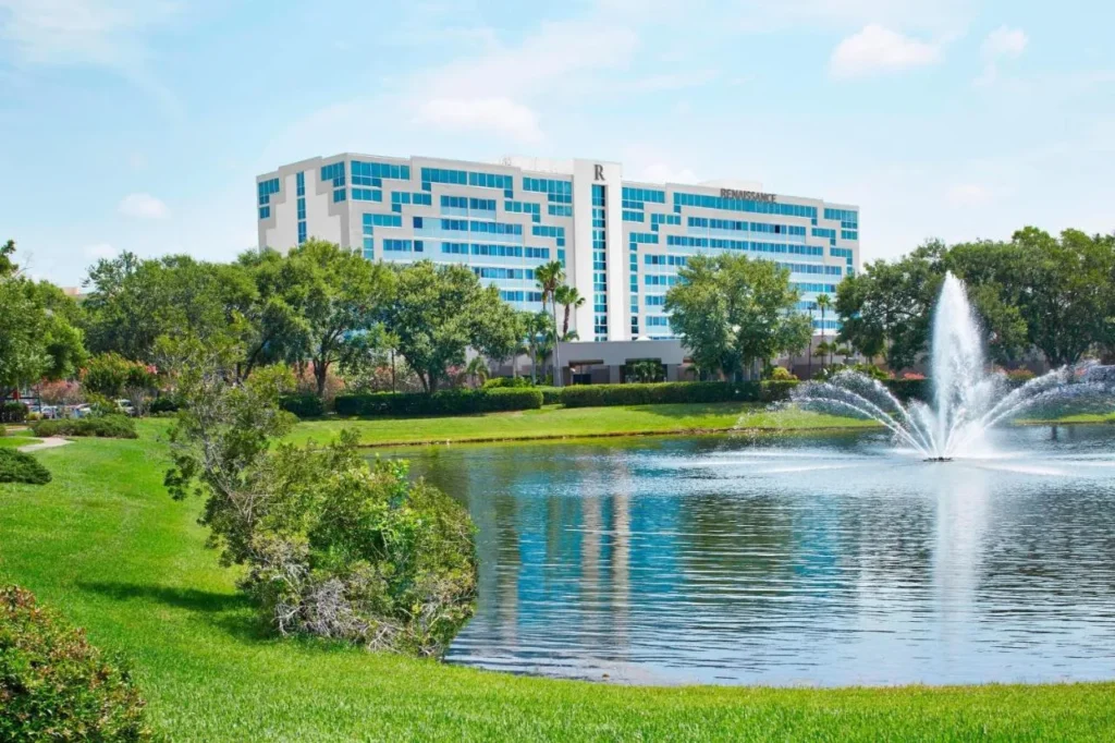 Renaissance Orlando Airport Hotel edificio detr&aacute;s de un lago con una fuente y c&eacute;sped